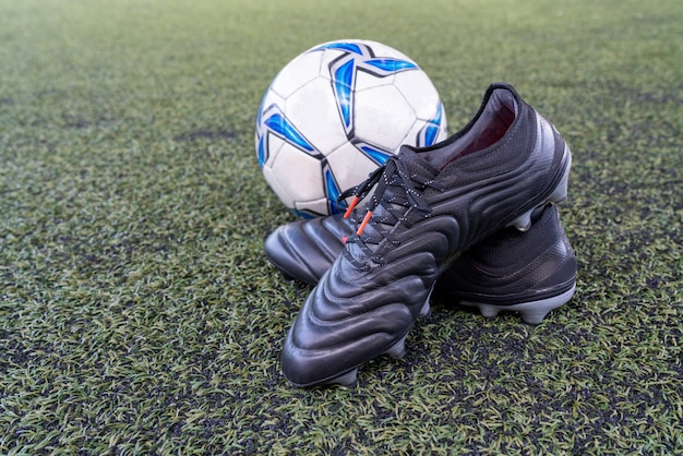 Photo football stud shoes with soccer ball on artificial grass field