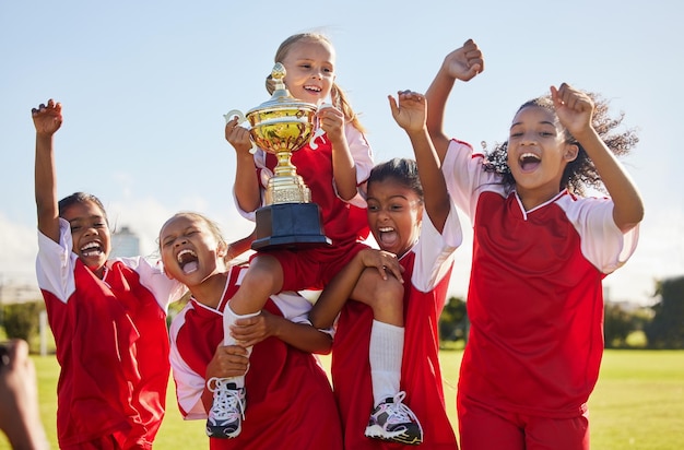 Football team and trophy with children in celebration together as a girl winner group for a sports competition Soccer teamwork and award with sport player kids celebrating success outdoor