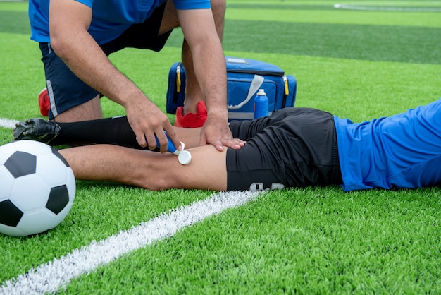 Photo footballer wearing a blue shirt, black pants injured in the lawn during the race.