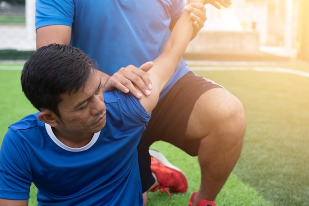 Photo footballer wearing a blue shirt, black pants injured in the lawn during the race.