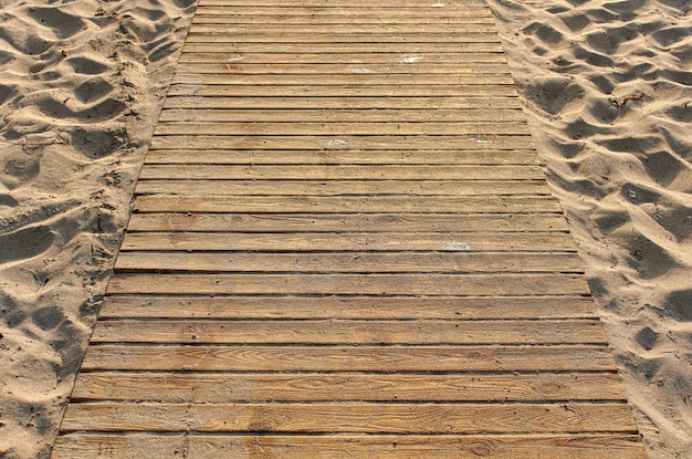 Photo footpath made of wooden boards on sandy beach, closeup detail