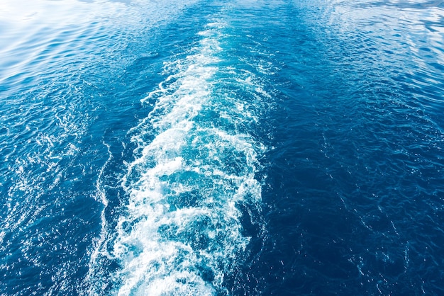 Footprint on the water from the ship White wave on blue water Blue sea water Water and sky