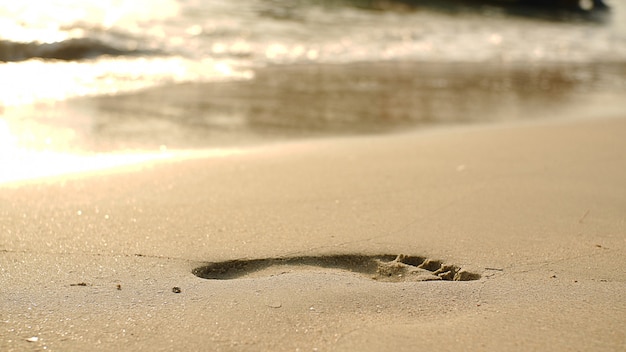 Photo footprints on beach sand and surging wave