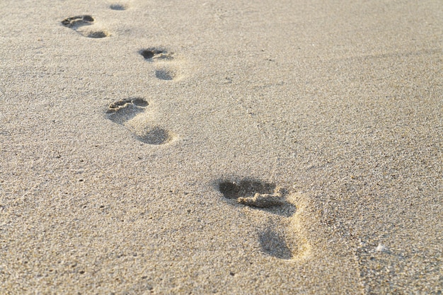 Footprints in the sand near the sea waves