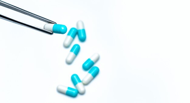 Forceps pick white-blue capsule from group of capsule pills