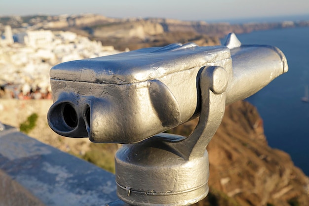 In the foreground a coin operated telescope in the background a view of the city of Fira Santorini Island Greece