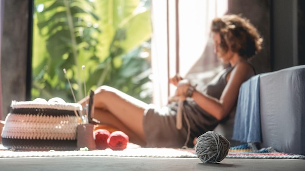 In the foreground is a ball of woolen thread in the background is a young woman