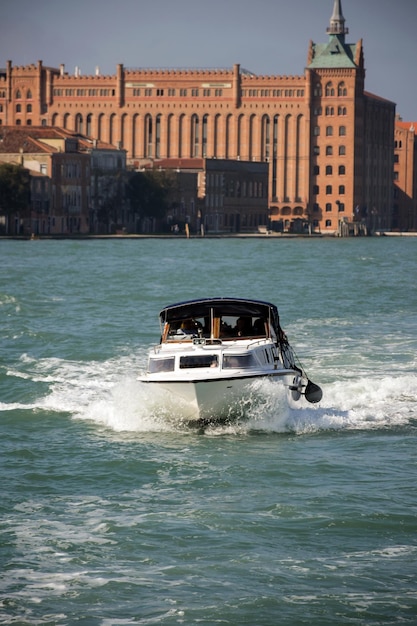 In the foreground, a motor boat with tourists floats on the waves. On the horizon behind her