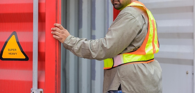 Foreman or technician worker opening container door to inspect container condition at shipping yard