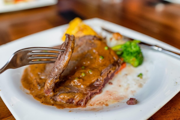 Fork dipping grilled rib eye beefsteak sliced