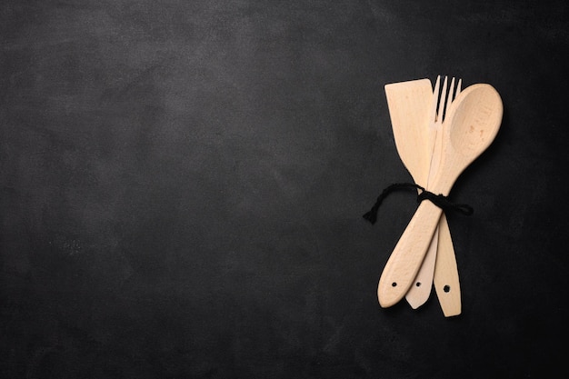 Fork and empty wooden spoon on a a black background top view