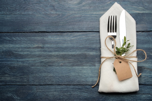 Fork, knife in a white napkin on a blue wooden table