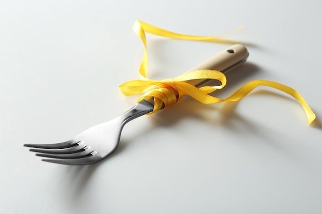 Fork tied with ribbon on light background