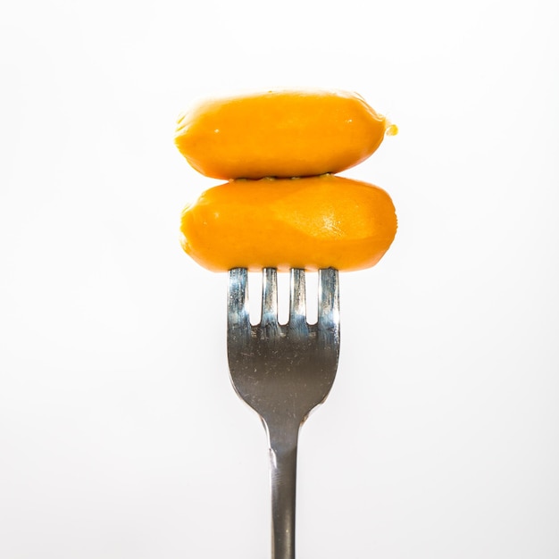 fork with small sausage ready to eat on white background.