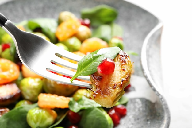 Fork with warm Brussels sprouts salad over table closeup