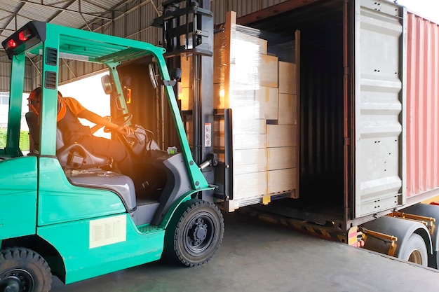 Forklift driver loading cargo pallet shipment into a truck container