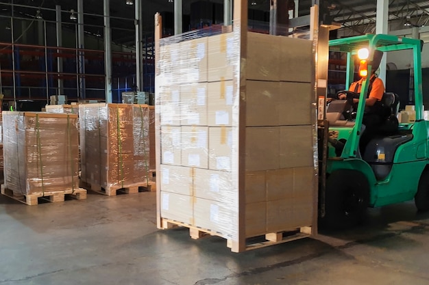 Forklift driver loading heavy shipment pallet goods in warehouse