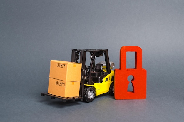 Forklift truck carries a cardboard box next to red padlock Embargo trade wars No delivery Restriction on the importation of goods proprietary for business Inability to sell products ban import