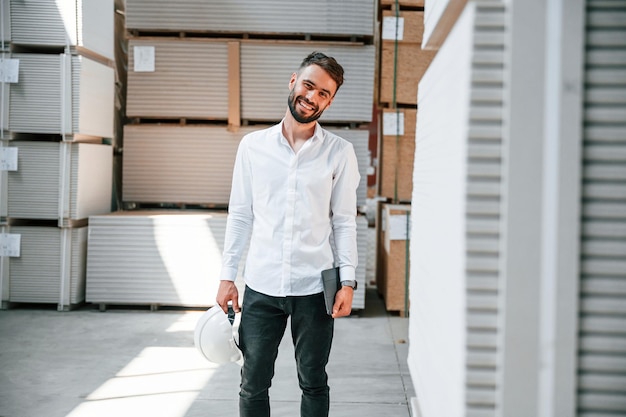 In formal clothes Storage worker is in the warehouse with bunch of products