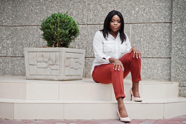 Formally dressed african american business woman in white blouse and red trousers Successful dark skinned businesswoman