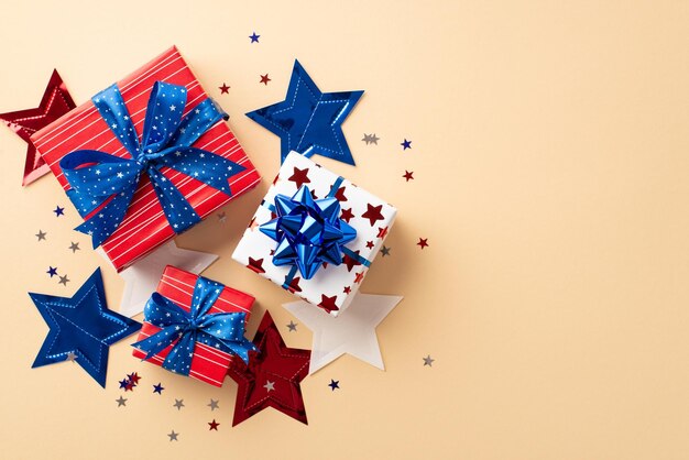 Forth of July concept Top view photo of present boxes in national flag colors with ribbon bows confetti and star garland on isolated beige background with copyspace