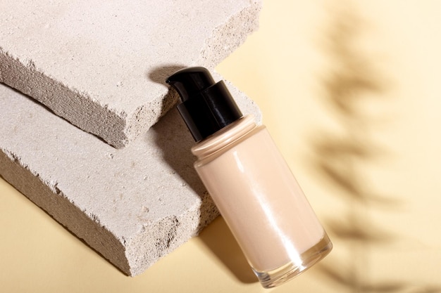 Foundation concealer on the background of stone geometric shapes Face corrector on beige background with copy space Packaging mockup with copy space