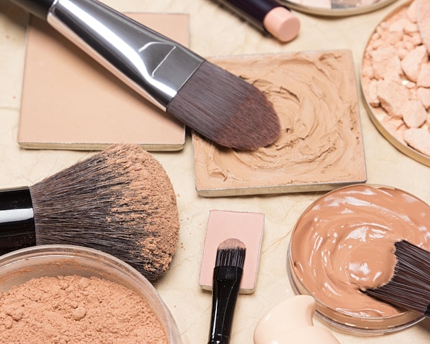 Foundation makeup products with make-up brushes on crumpled kraft paper