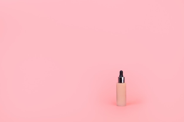 Foundation with a female hand on pink background BB cream for professional makeup