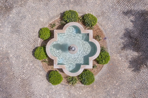 The fountain in the garden of cobblestones, shot from above from the sky, drone.