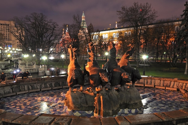 A fountain with a group of ducks on it at night.