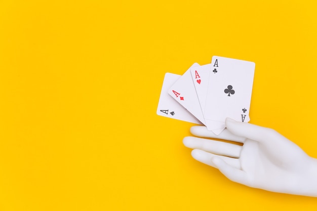 Four aces in mannequin hand on yellow background