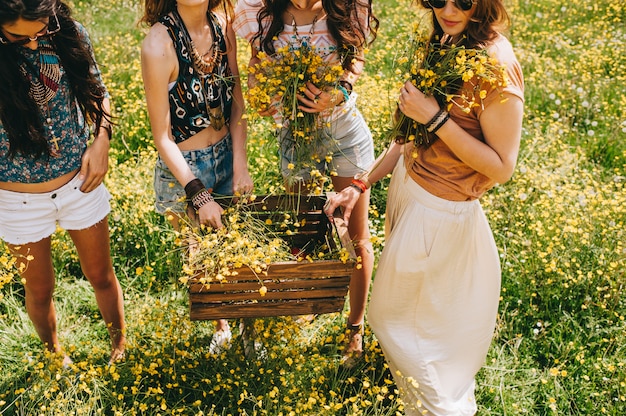 Photo four beautiful hippie girl in a field of yellow flowers