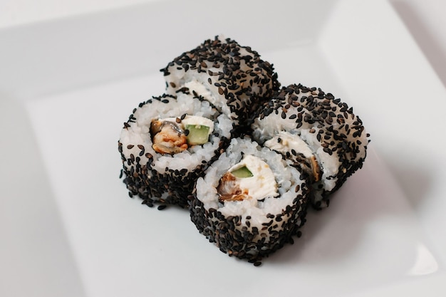 Four black sushi maki rolls decorated with greenery