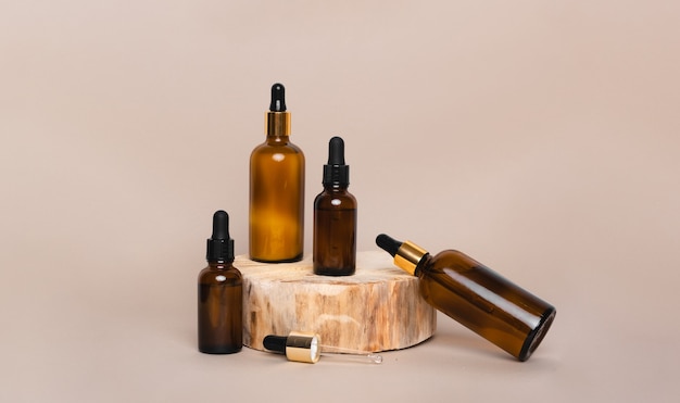 Four brown glass bottles with pipettes on wooden podium  isolated on beige background