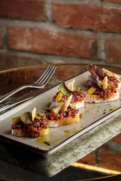 Four bruschettas with beef tartare on a plate Crostini with Beef Tartare beef Bruschetta sandwich with raw gourmet beef