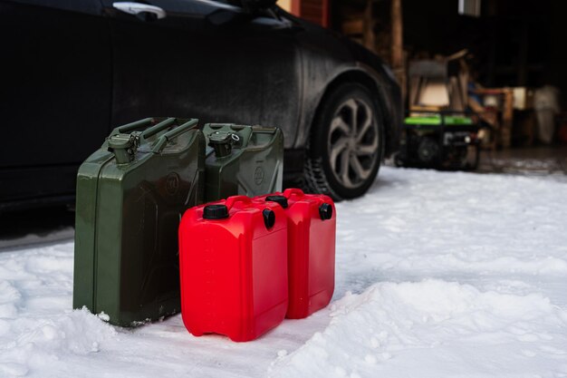 Four canisters with gasoline stand in snow against car