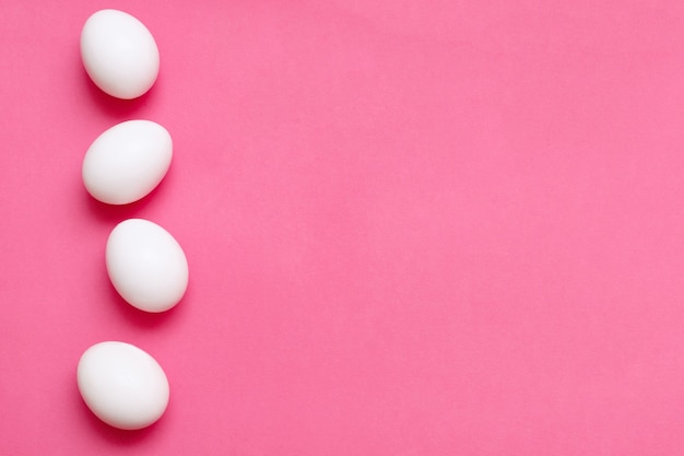 Four chicken eggs on a bright pink surface