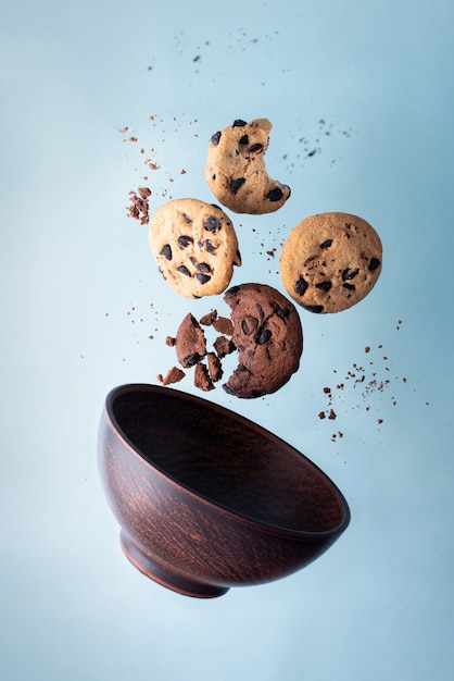 Four chocolate chip cookies and a bowl flying