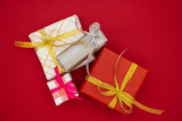 Four Christmas gift boxes on a red background. Christmas and new year concept. Top view