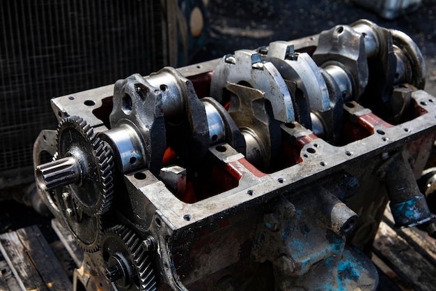 A four-cylinder engine dissembled and removed from car on a workbench in a vehicle repair workshop.