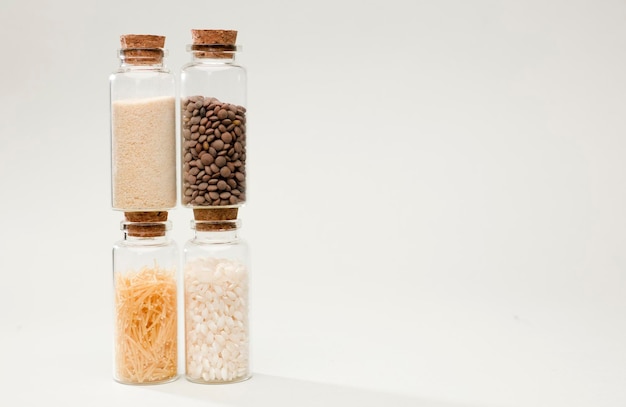 four glass jars with cork stopper, bread, lentils, pasta and rice, soft greenish background