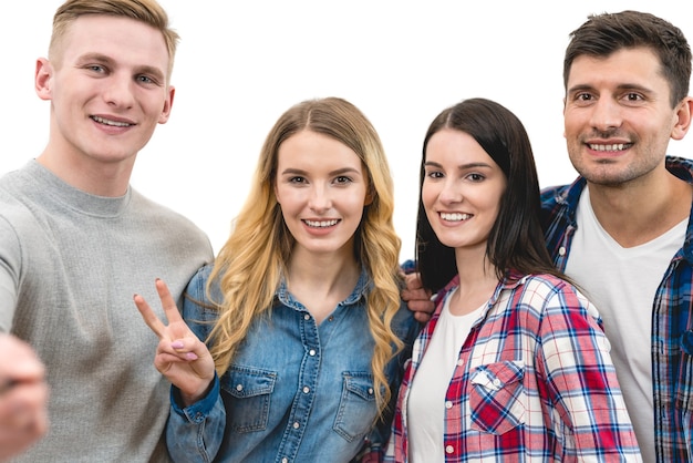 The four happy friends make a portrait selfie on the white background