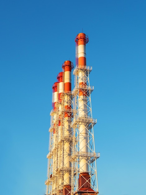 Four industrial chimneys against a blue sky