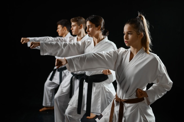 Four karate fighters poses in white kimono, group training. Karatekas on workout, martial arts, fighting competition