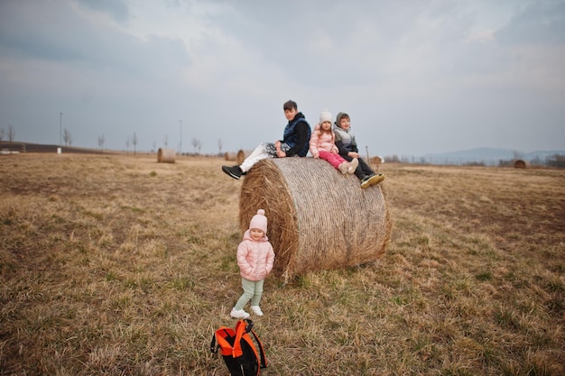 Four kids sitting on haycock at field