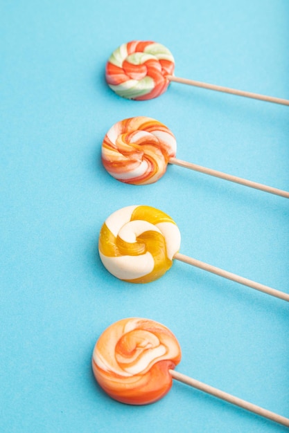 Four lollipop candies on blue background copy space side view