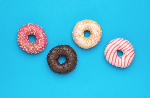 Four multicolored glazed donuts on a blue background The minimal concept of popular baking