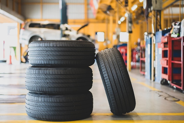 Four new tires lie on the floor inside the garage and blur cars and repair equipment in the background