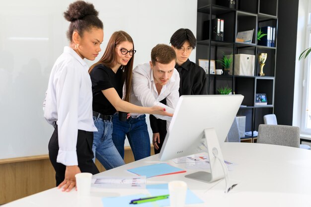 Four people of different nationalities are working on a project in the office