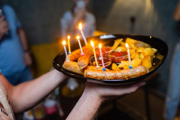 Four people hold a hot dog together